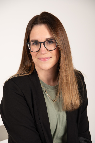 Woman with long brown hair and glasses smiling at the camera