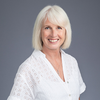 Woman with short grey hair smiling at the camera