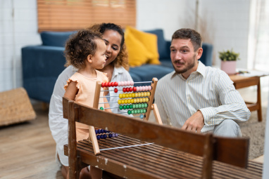 Mother and father with young child at home playing with abacus