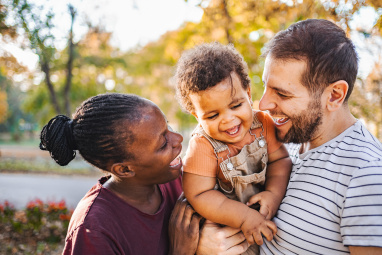 Man holding young child with woman alongside, all are smiling