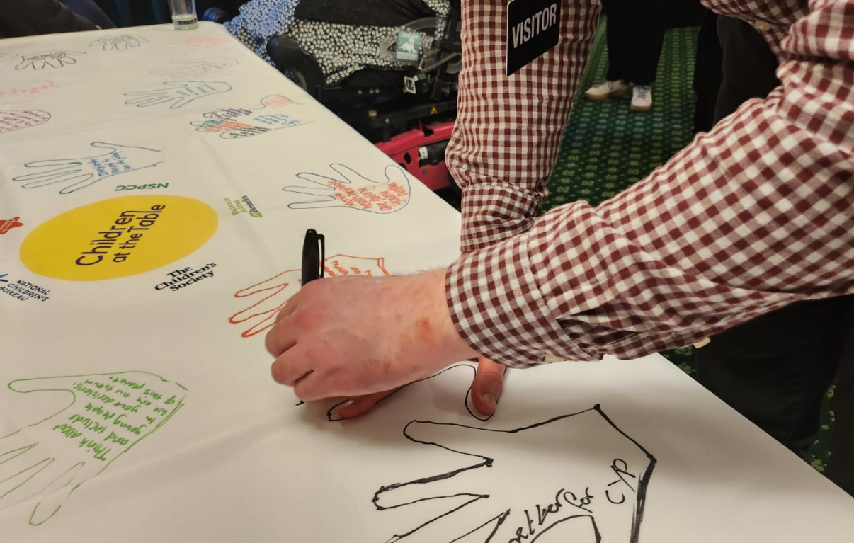Image of young person drawing their handprint onto the tablecoth 