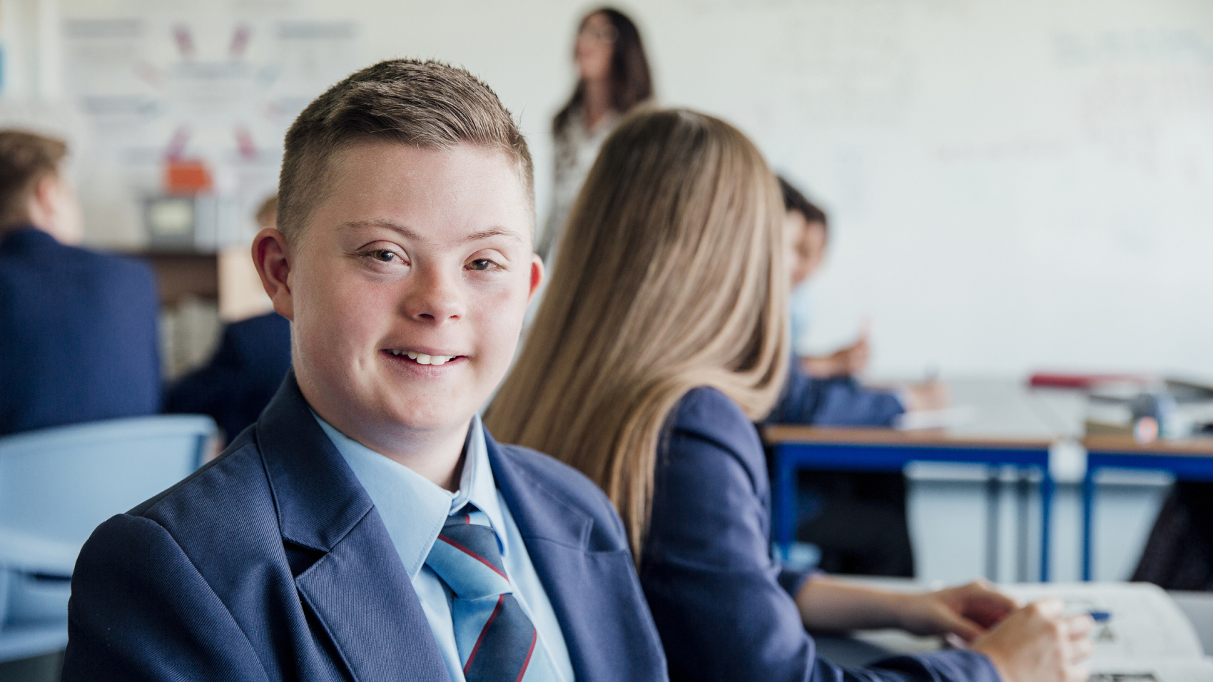 A boy in school uniform looks into the camera.