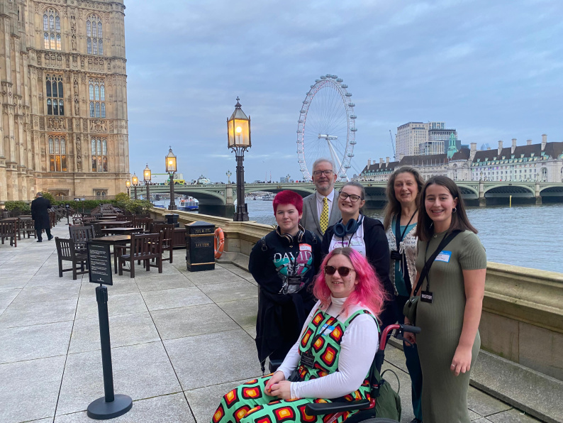 Group of young people gathered outside of Parliament, in front of the london eye. 