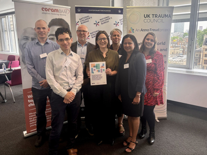 Group of people who have been involved in writing the report standing in front of banners at the launch event