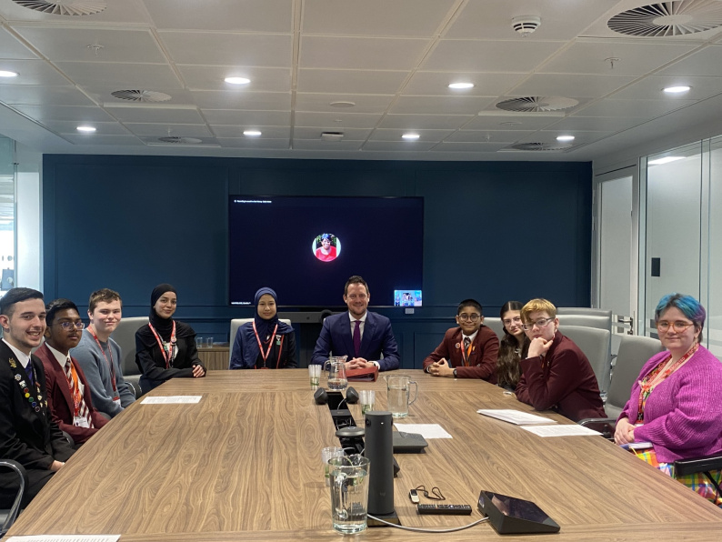 Image of young people and Minister Stephen Morgan sat around a table smiling at the camera..