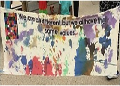 A mural with splashes of different colour paint and a message that reads We are all different but we have the same values 