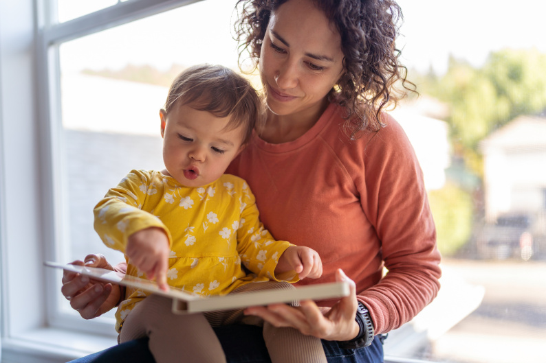 Mother reading together with early years child