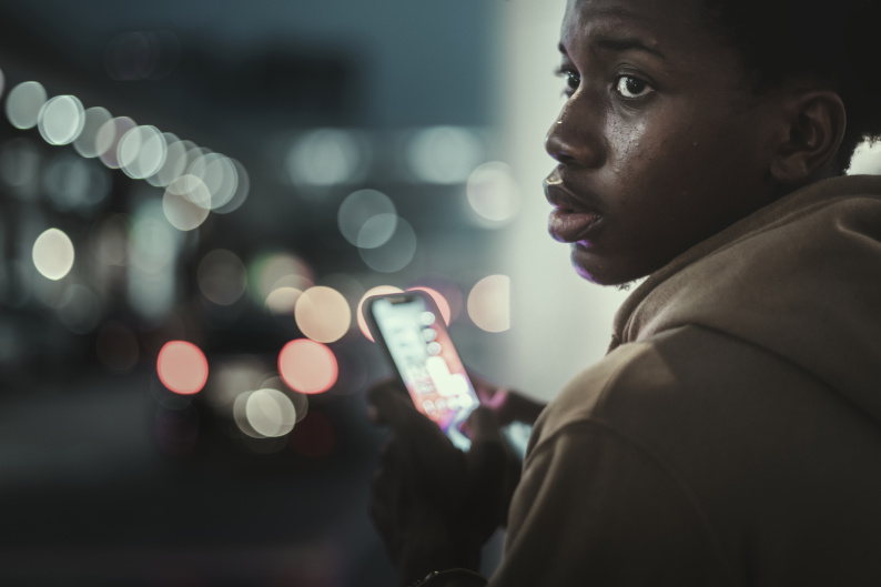 Young person turning to his left while holding a mobile phone