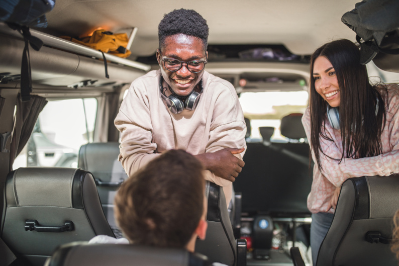 Three young people laughing on a minibus