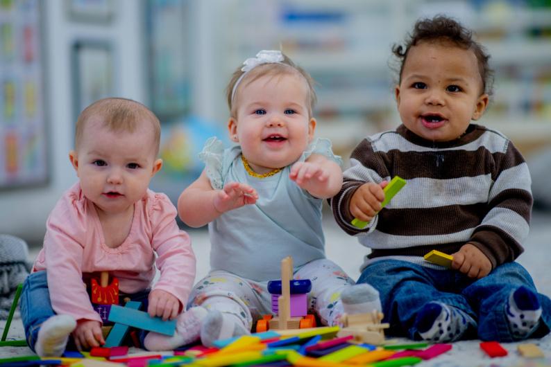 Three young children playing together in a nursery setting