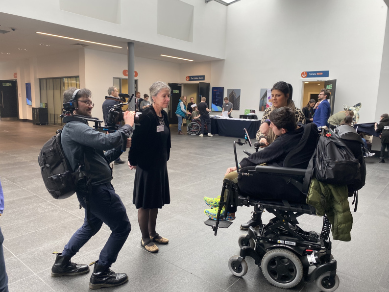 A boy in a wheelchair interviewing NCB Chair whilst being filmed by a videographer